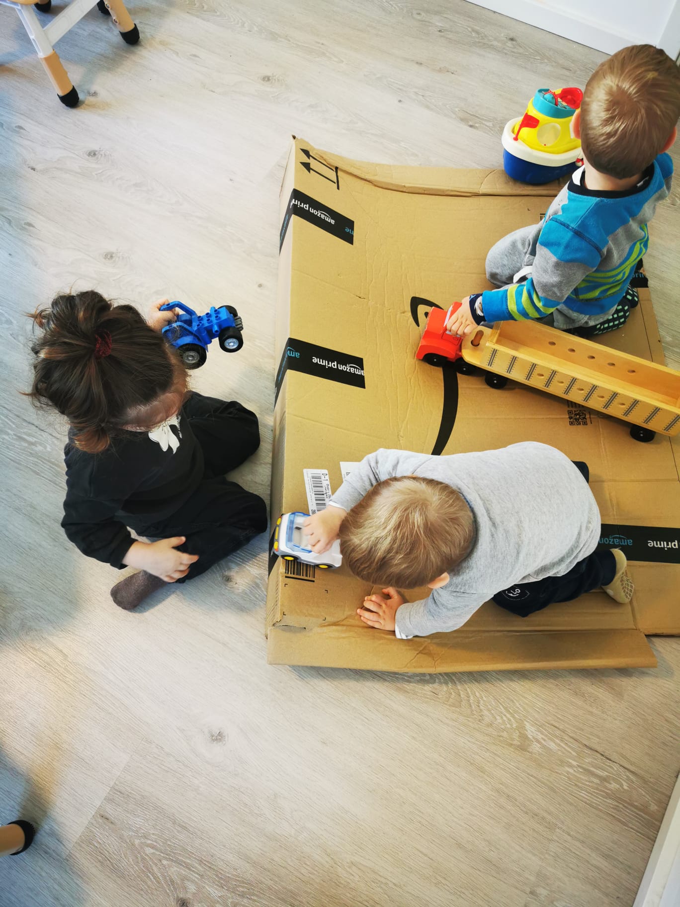 Kinder spielen mit Autos auf Karton